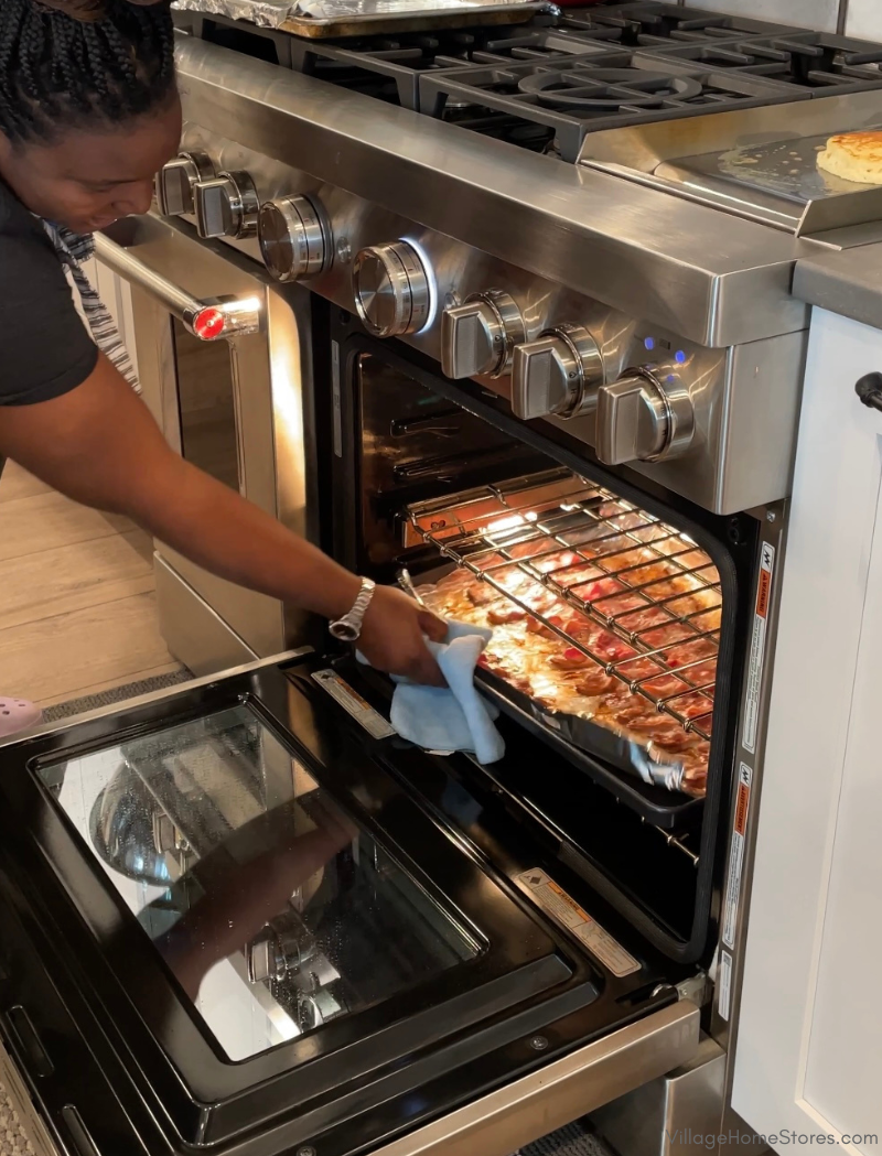 chef keys opening stainless steel oven door and removing tray of bacon from inside
